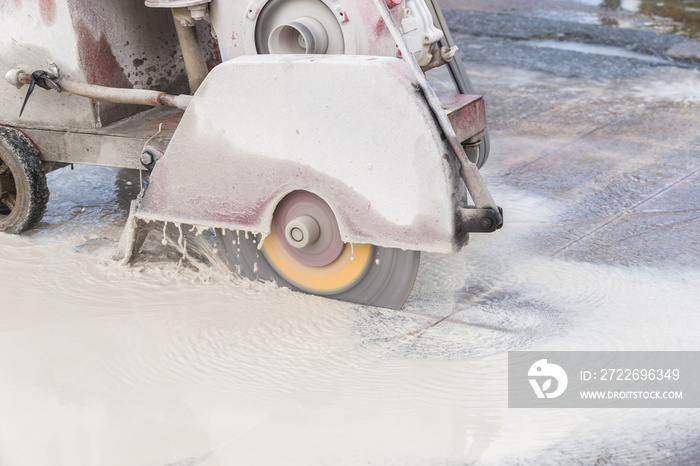 Worker cutting concrete road with diamond saw blade machine