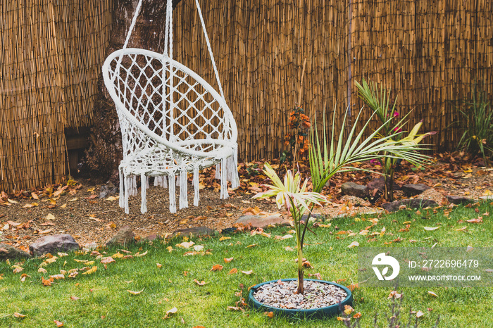 idyllic backyard with autumn tones and fallen leaves on the grass with boho hippie hanging chair