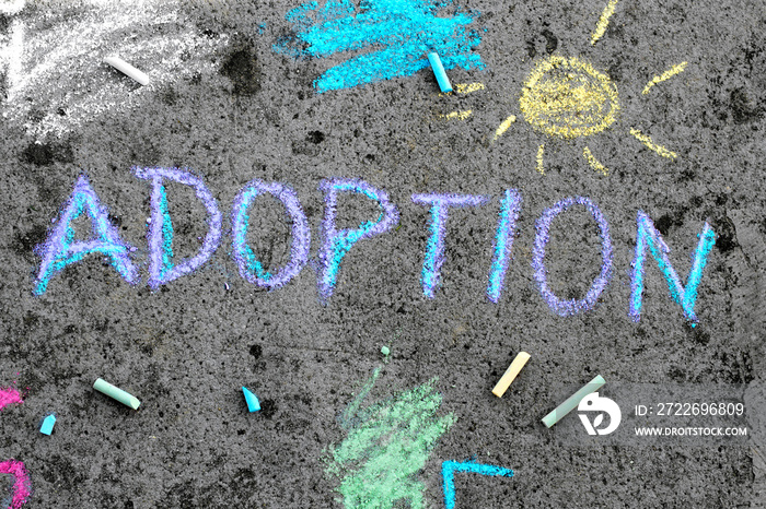 Colorful chalk drawing on asphalt: word ADOPTION