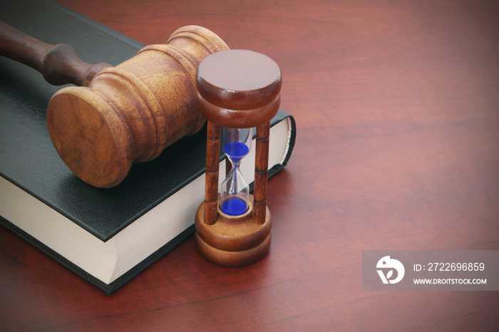 Judge gavel, hourglass and legal book on brown wooden table