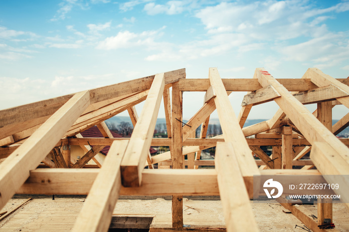 Installation of wooden beams and timber at construction site. Building the roof truss system structure of new residential house