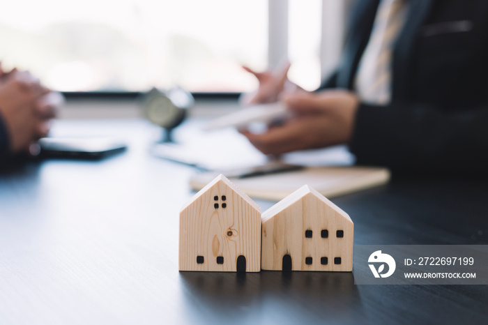 House sales deals with real estate agents with a small house model in the foreground.