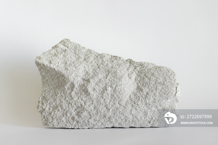 Large white building stone with visible porous surface on white background.