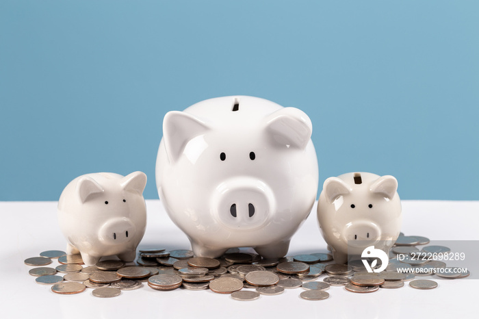 Family piggy bank, white ceramic piggy bank on stack coins on white wood table, saving money, financial planning.