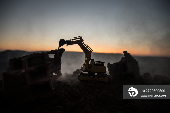 Construction site on a city street. A yellow digger excavator parked during the night on a construction site. Industrial concept table decoration on dark foggy toned background