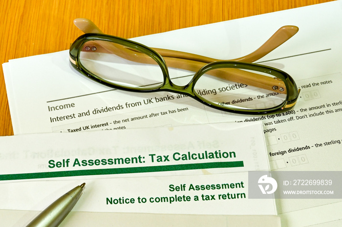 Close up view of a self assessment tax return form on a wooden table with a pen and a pair of glasses