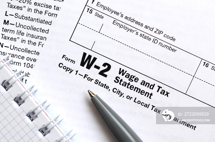 The pen and notebook on the tax form W-2 Wage and Tax Statement. The time to pay taxes