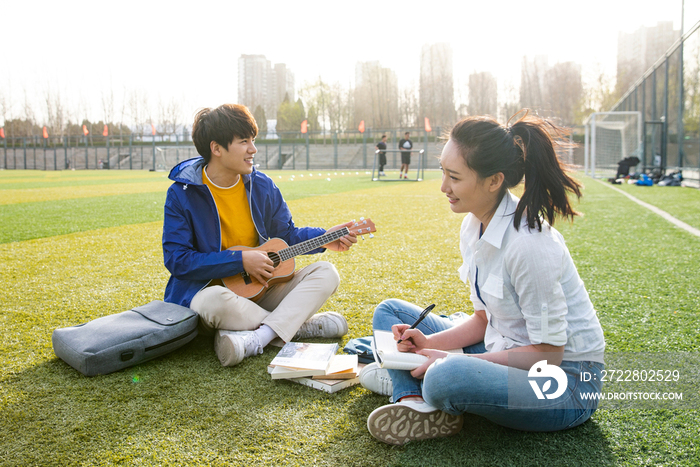 青年大学生在校园里弹奏吉他