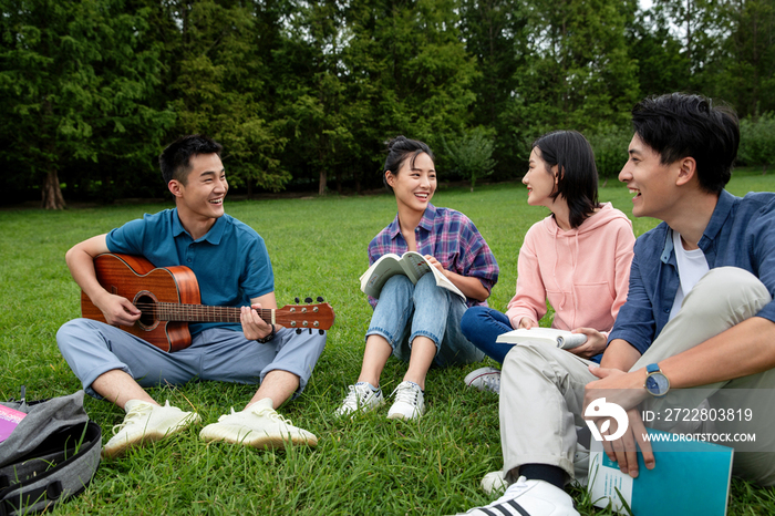 快乐的大学生在草地上弹吉他唱歌