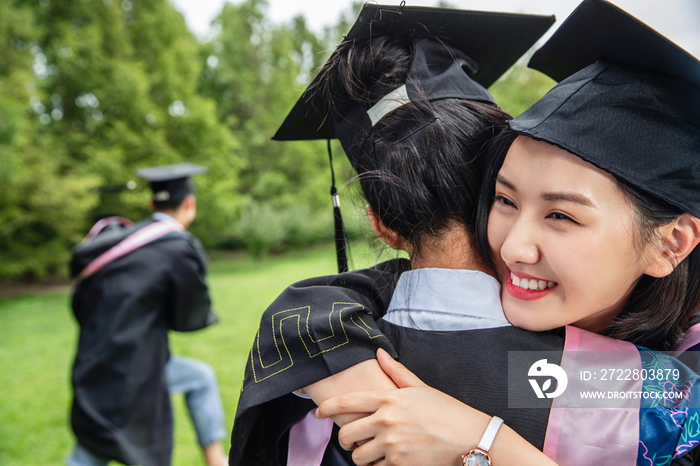 户外穿着学士服的大学生拥抱庆祝