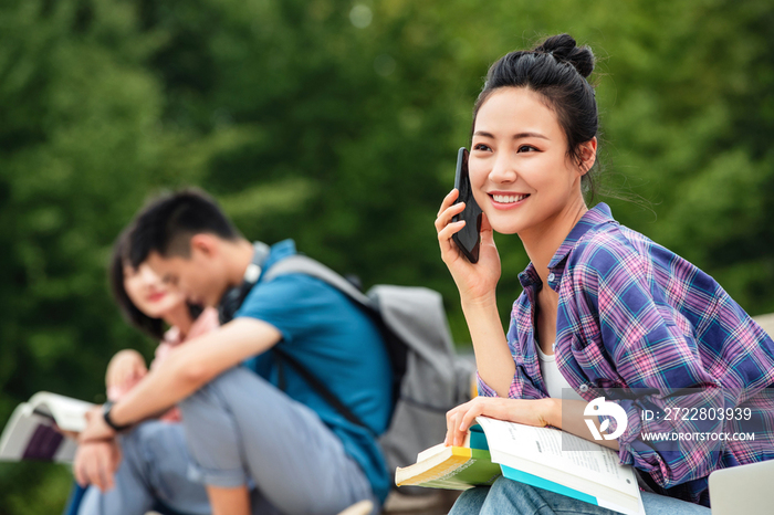 快乐的大学生坐在台阶上打电话