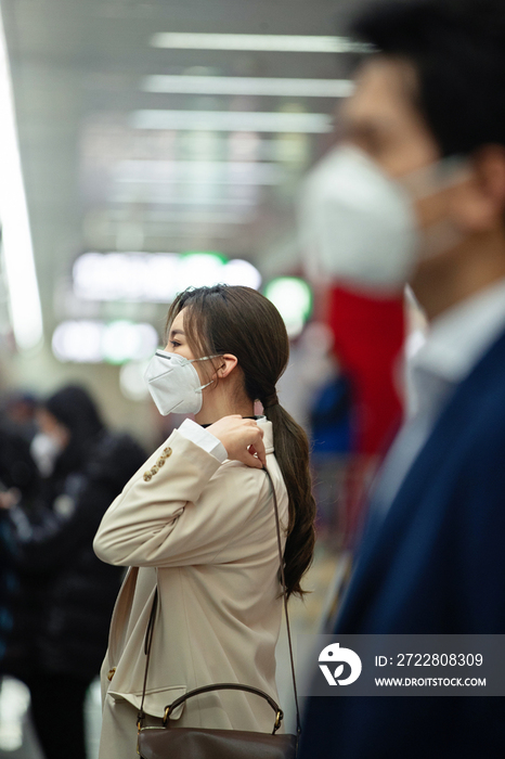 戴口罩的年轻女人站在地铁站台上