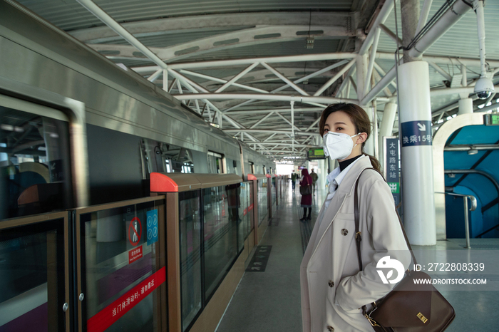 戴口罩的年轻女人站在地铁站台上