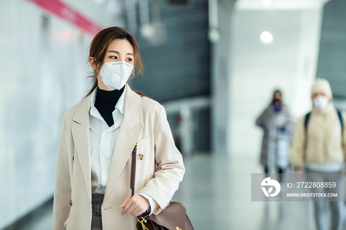 戴口罩的年轻女人走在地铁站里