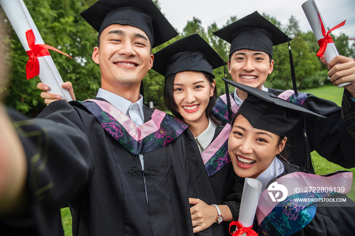 四个身穿学士服的大学生一起自拍