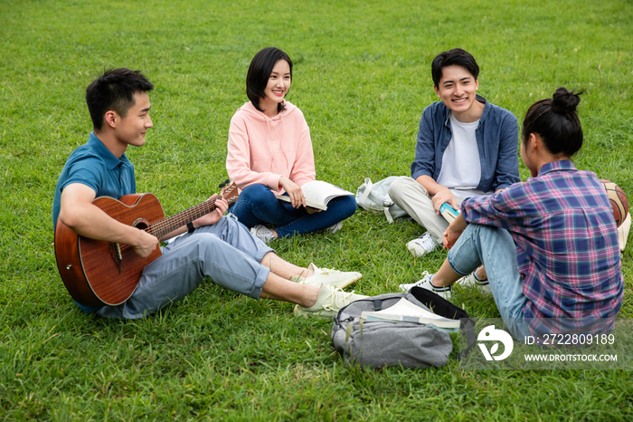 快乐的大学生在草地上弹吉他唱歌