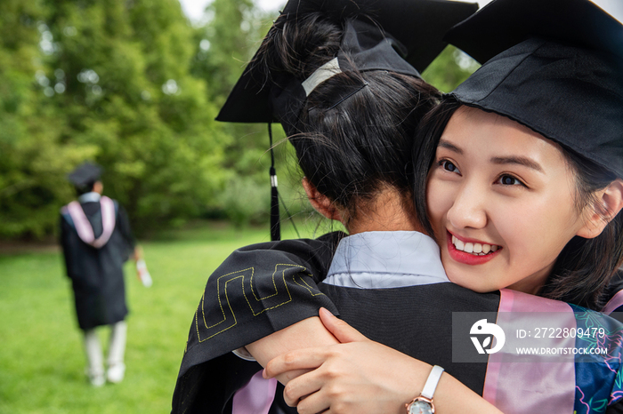 户外穿着学士服的大学生拥抱在一起