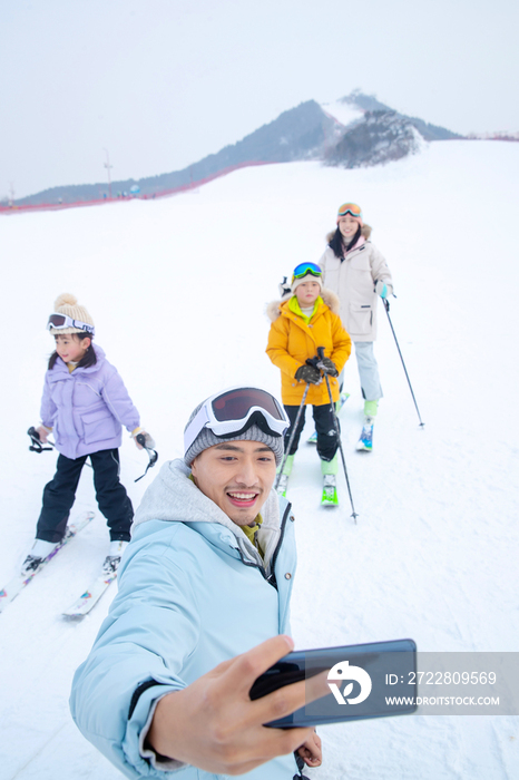 滑雪场上用手机自拍的一家四口