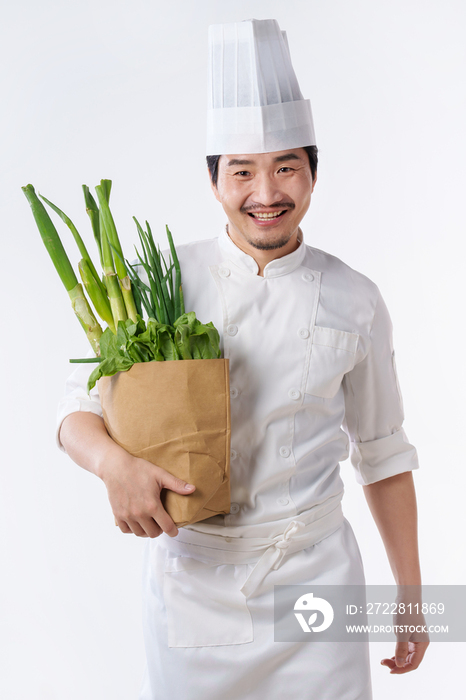 穿着厨师服的中年男人抱着蔬菜