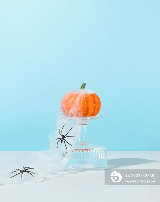 Minimal spooky Halloween concept made of pumpkin on glass podium with spiders web and spiders on sk