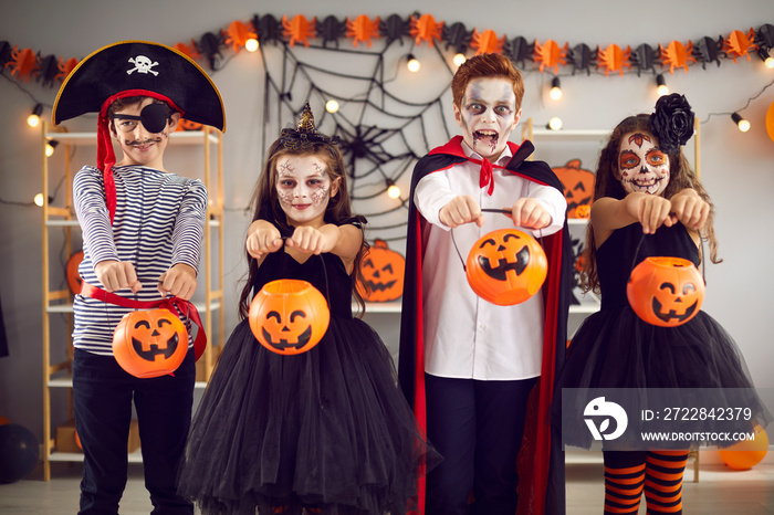 Kids are ready for tricks or treats on Halloween night. Four children standing in room in carnival c