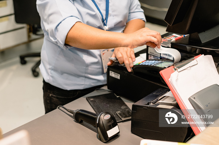 Cashier hand printing and taking receipt from pos terminal.