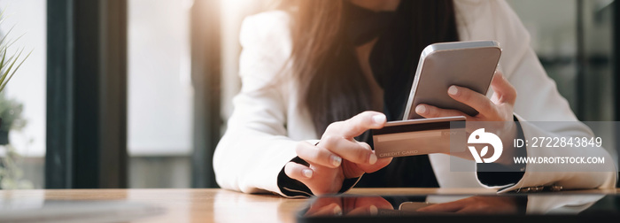 Close up female hands holding credit card and smartphone, young woman paying online, using banking s