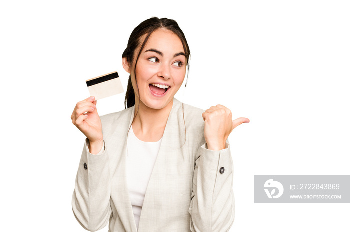 Young caucasian woman holding a credit card isolated on green chroma background points with thumb fi