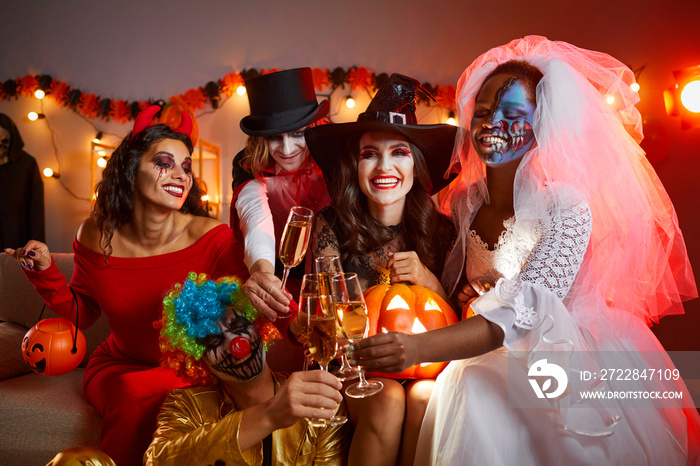 Happy young multiracial people drinking and having fun at Halloween party at home. Diverse group of 