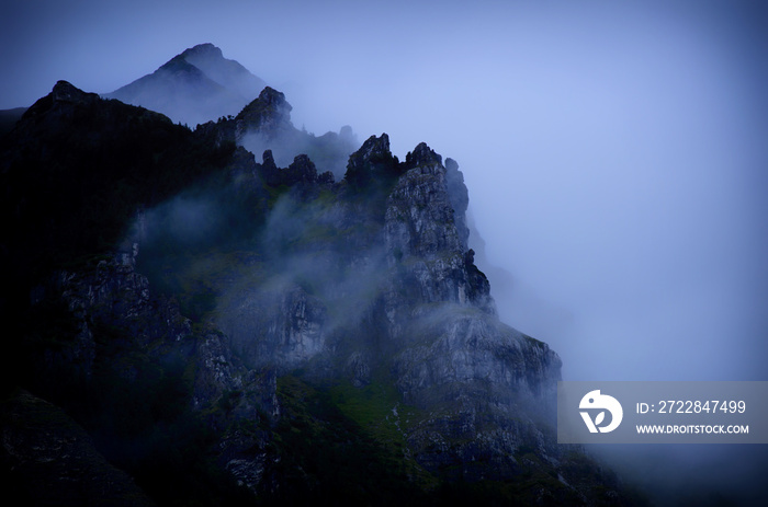 Spooky foggy mountains and woods in the evening (in dark blue tones)