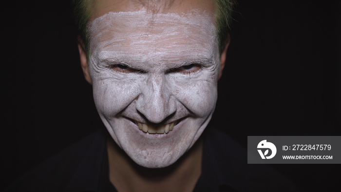 Clown Halloween man portrait. Close-up of an evil clowns face. White face makeup