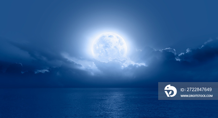 Night sky with moon in the clouds on the foreground blue sea  Elements of this image furnished by NA