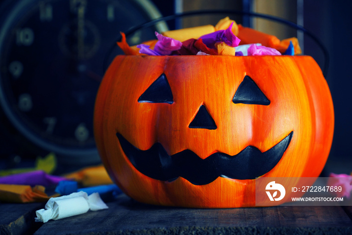 Pumpkin decorate with candy on wood table and dark background.