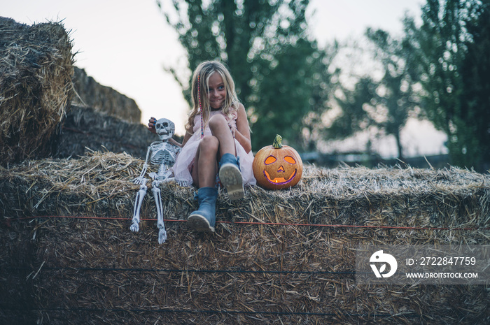 Blond girl blue eyes with pumpkin and skeleton halloween