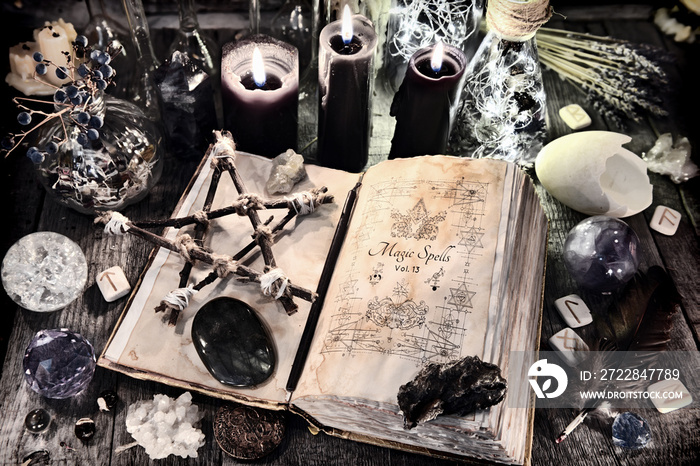 Open witch book with pentagram, black candles, stones, crystals and magic ritual objects. Halloween,