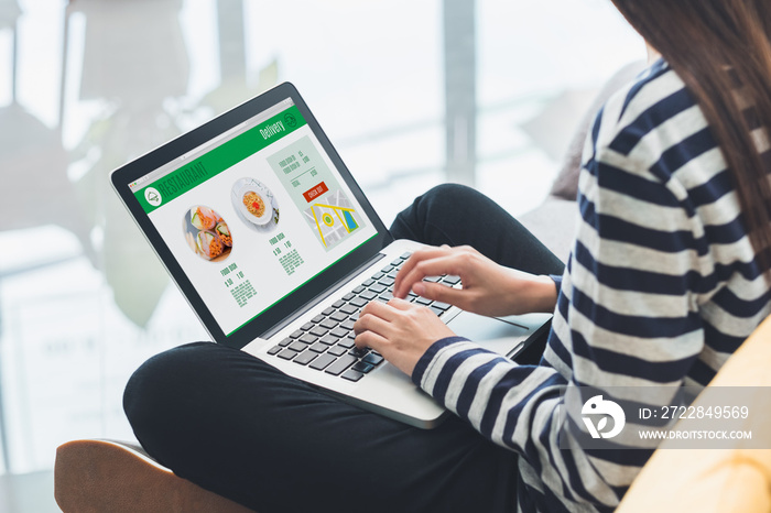 Asian woman cross leg sitting at couch use laptop to order food online in website at home.digital le