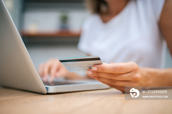 Close-up image of female person using credit card for online shopping.