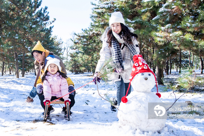 在雪地上玩雪橇的一家人