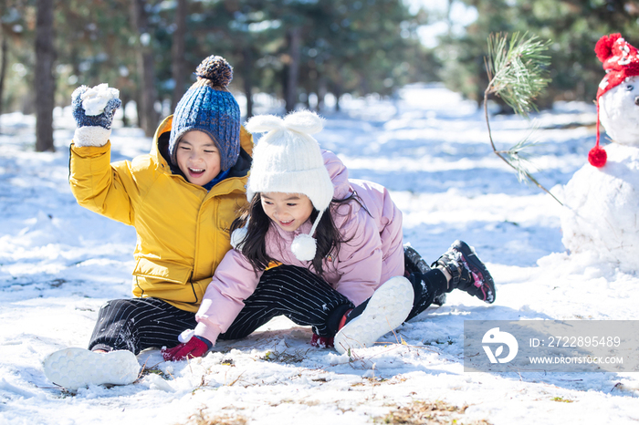 坐在雪地上玩耍的儿童和雪人