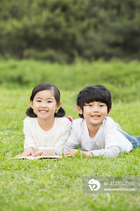 小男孩和小女孩趴在草地上