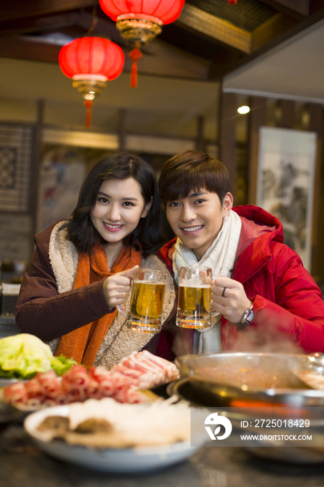 年轻情侣在火锅店吃饭喝啤酒