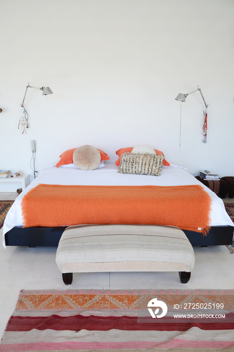 Orange throw rug and foot stool in middle class home