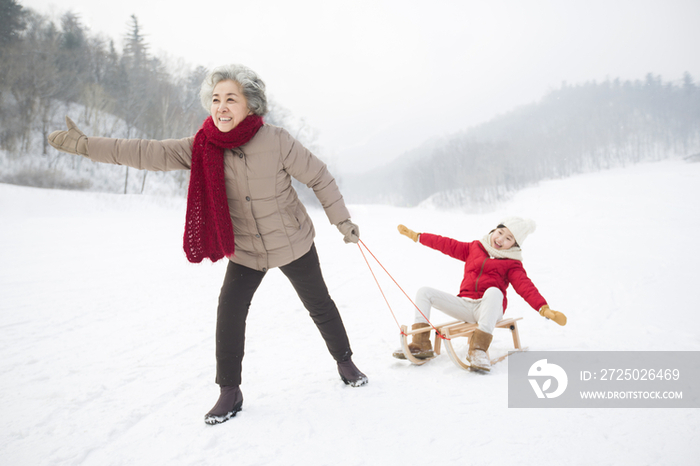 奶奶和孙女在雪地上玩雪橇