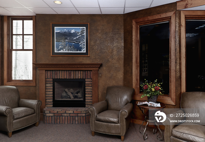 Leather armchairs by fireplace in middle class house