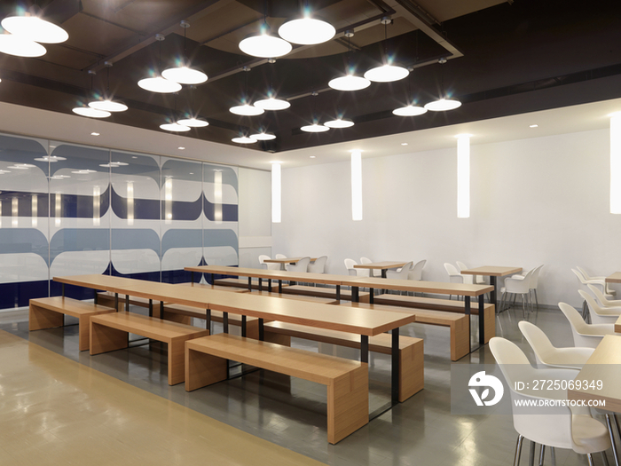 Ceiling lights over wooden benches and empty tables with designed wall in the restaurant