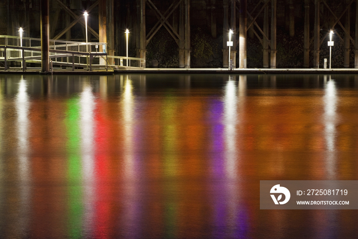 Neon lights reflect off Sacramento River at night