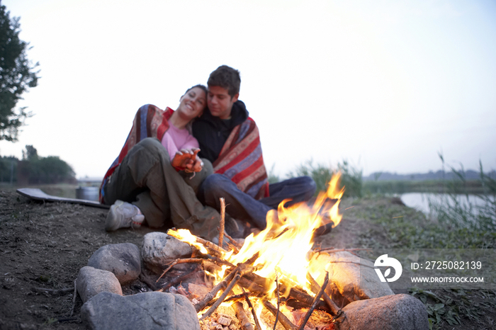 年轻情侣坐在篝火旁