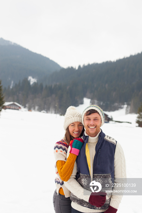 Portrait happy couple in warm clothing in snowy field