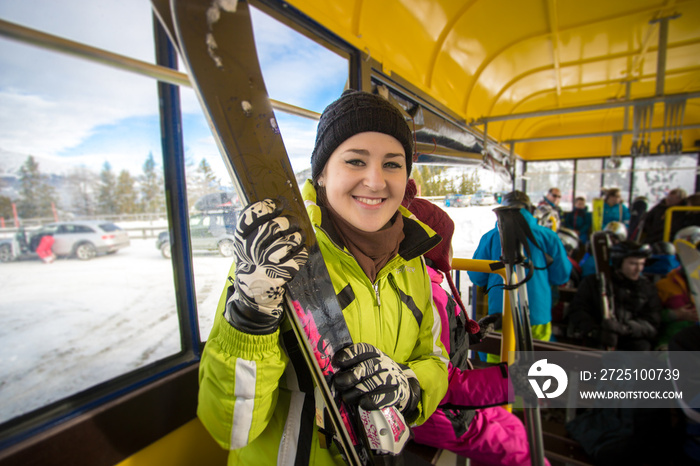 微笑的女人带着滑雪板坐在公交车上的画像