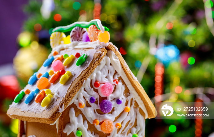 Gingerbread house with glaze standing on table with decorations Christmas tree.